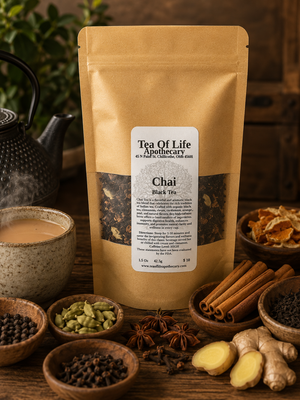 Tea of Life Apothecary Chai Black Tea displayed with traditional chai spices including cinnamon sticks, cardamom pods, cloves, black peppercorns, fresh ginger, star anise, orange peel, loose black tea, a steaming cup of chai, and a cast iron teapot on a rustic wooden table.