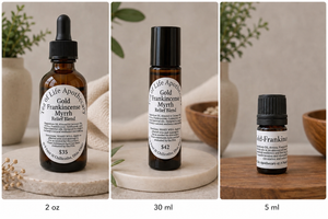 Gold Frankincense and Myrrh pain and neuropathy essential oil blend from Tea of Life Apothecary displayed in 2 oz, 30 ml, and 5 ml amber bottles with calming natural wellness decor and soft neutral lighting.