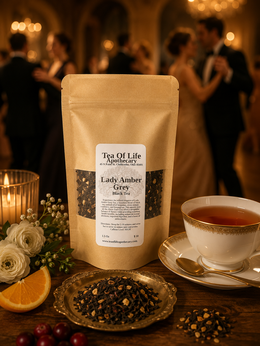 Tea of Life Apothecary Lady Amber Grey Black Tea displayed with a fine china teacup, loose black tea, fresh orange slices, cranberries, and elegant floral accents on a rustic wooden table. A softly blurred ballroom with elegantly dressed couples dancing in the background evokes the refined, classic character of this bergamot-infused black tea blend.