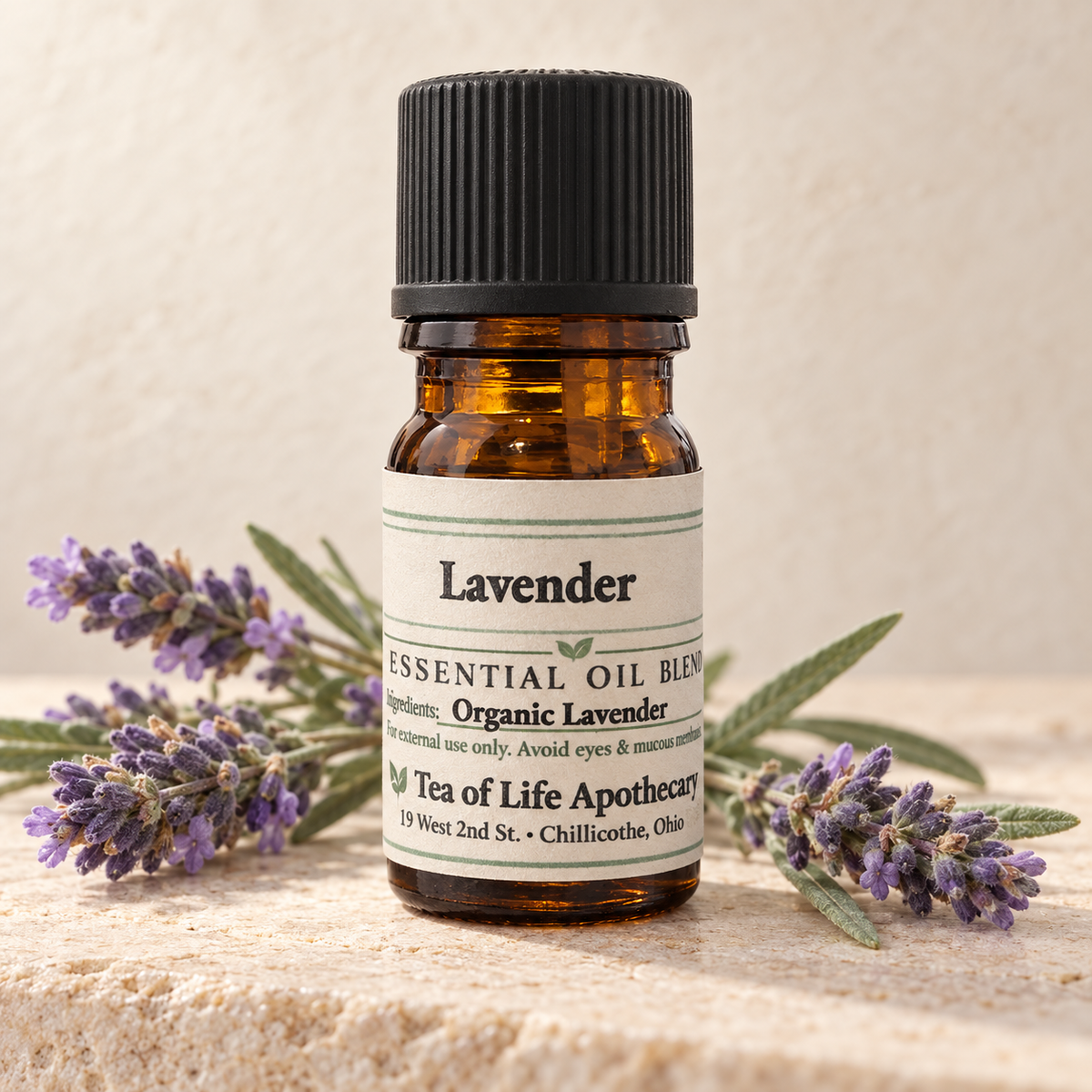 Tea of Life Apothecary Organic Lavender Essential Oil in a 5 mL amber glass bottle, displayed with natural lavender flowers and silvery-green foliage.