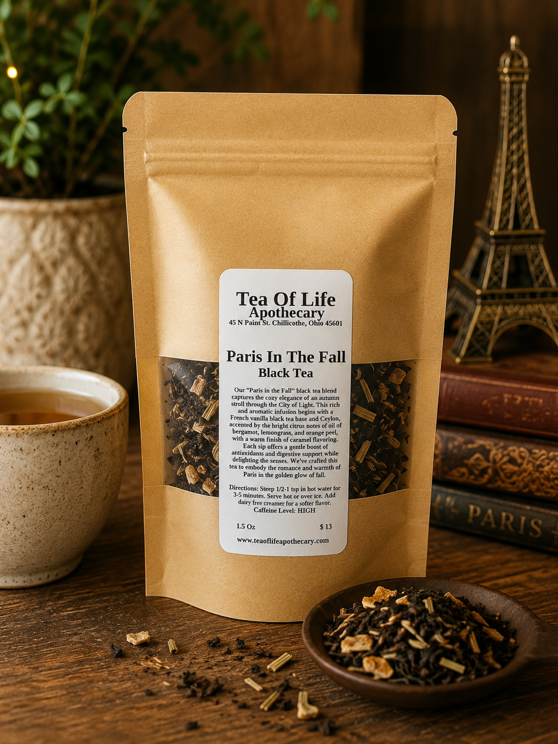 Tea of Life Apothecary Paris in the Fall Black Tea in a resealable kraft pouch displayed beside a warm cup of black tea with loose tea leaves, bergamot peel, and French vanilla-inspired accents on a rustic wooden table. This aromatic loose-leaf black tea features notes of French vanilla, bergamot, lemongrass, orange peel, and caramel for a cozy autumn-inspired tea experience.