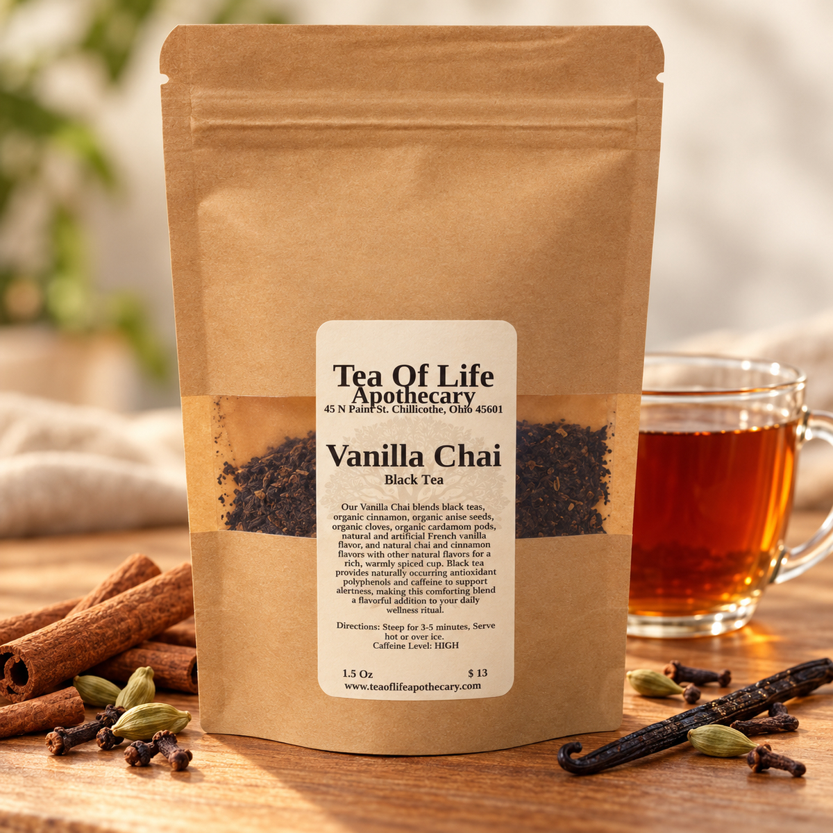 Tea of Life Apothecary Vanilla Chai Black Tea pouch with cinnamon sticks, cardamom pods, cloves, vanilla beans, and a glass cup of amber tea.