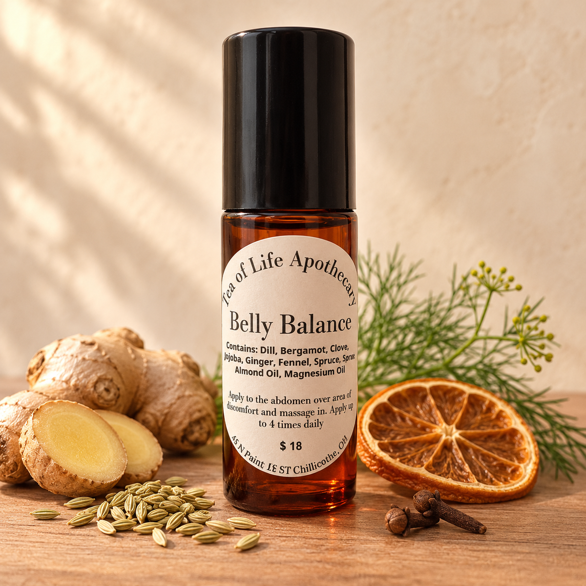 Tea of Life Apothecary Belly Balance topical abdominal massage roller displayed with ginger, fennel, bergamot, cloves and fresh botanicals. A soothing essential-oil blend designed to be massaged over the abdomen for comforting topical support.