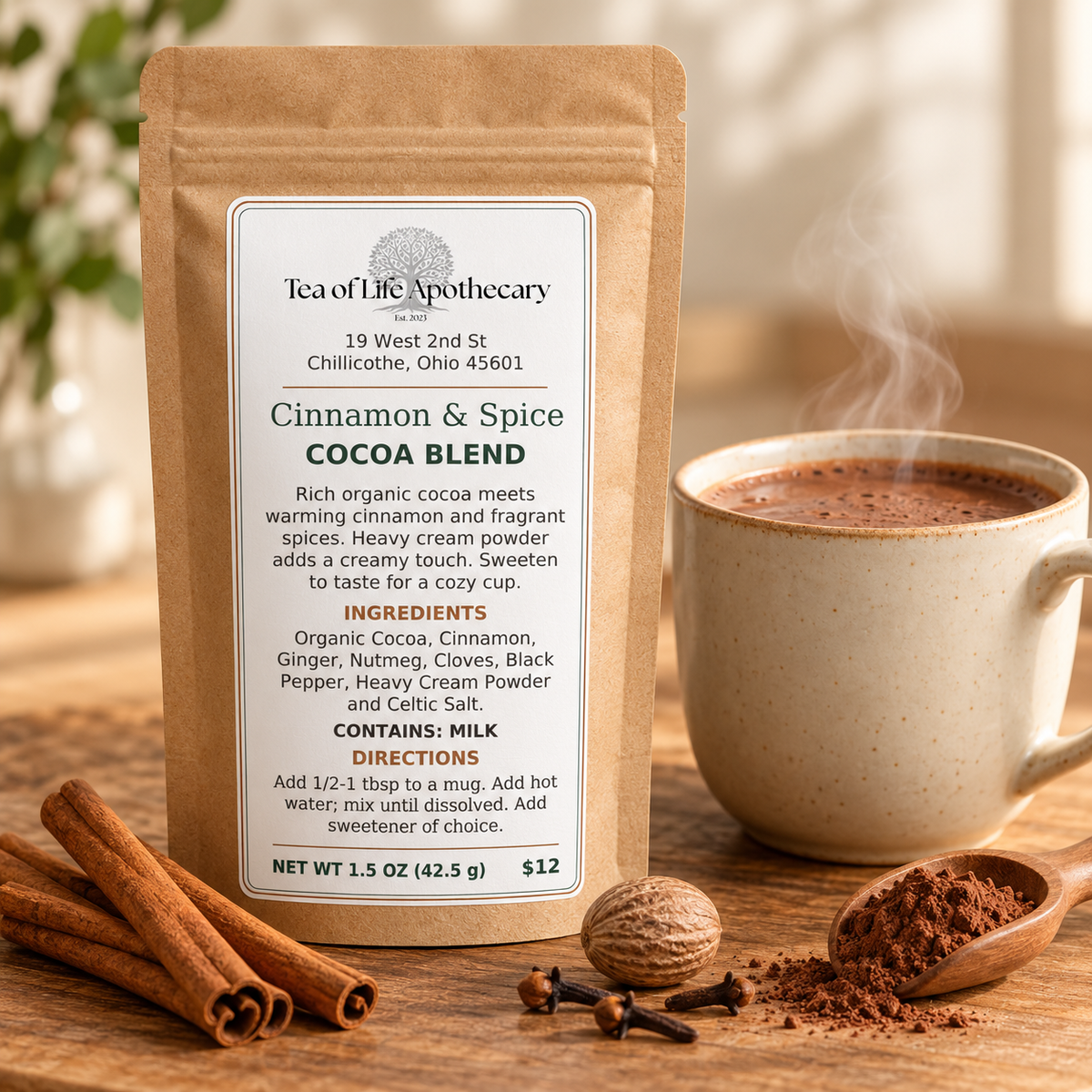 Tea of Life Apothecary Cinnamon & Spice Cocoa Blend in a kraft pouch beside a steaming mug of hot cocoa, cinnamon sticks, nutmeg, and cloves.
