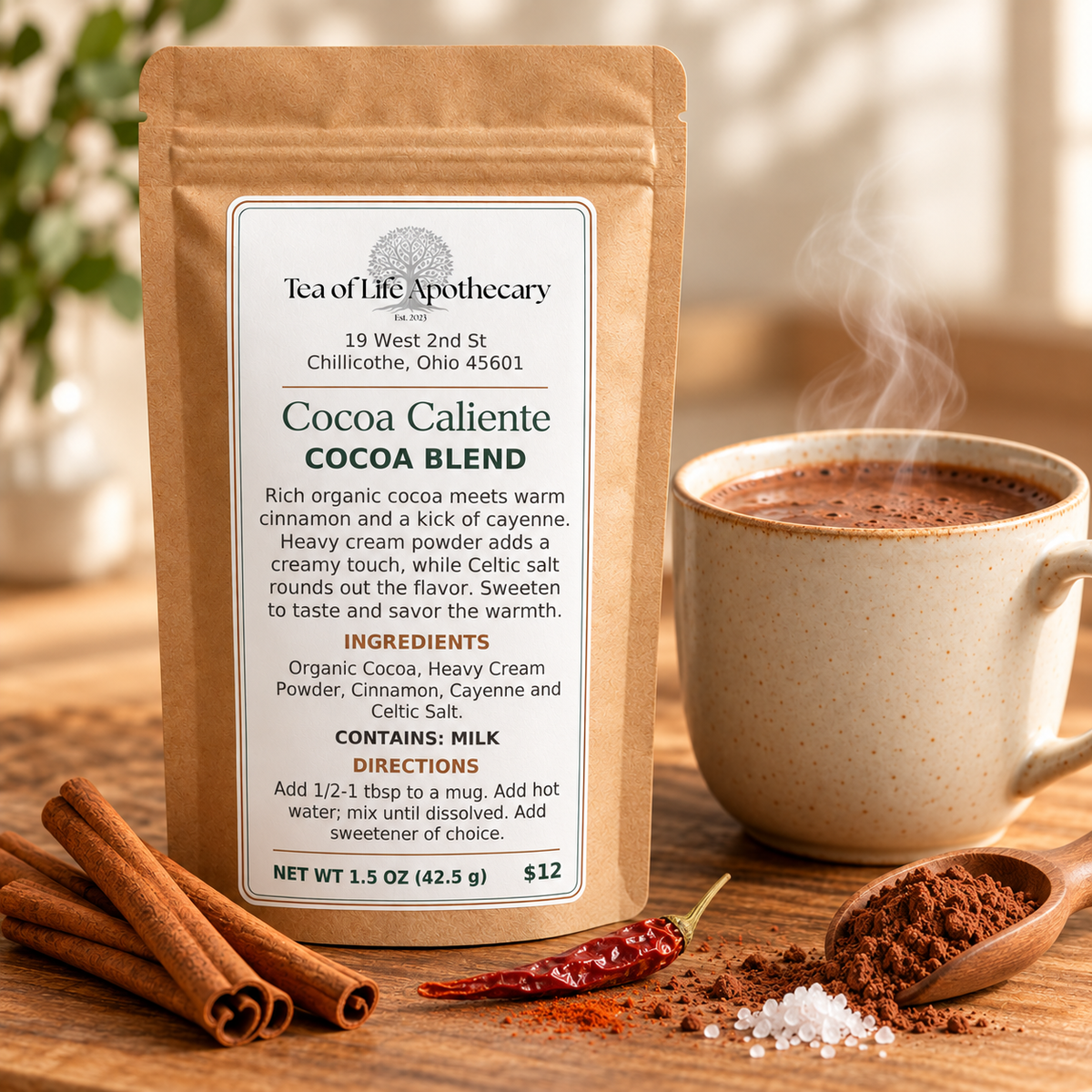 Tea of Life Apothecary Cocoa Caliente blend in a kraft pouch beside steaming hot cocoa, cinnamon sticks, a dried cayenne pepper, cocoa powder, and salt.