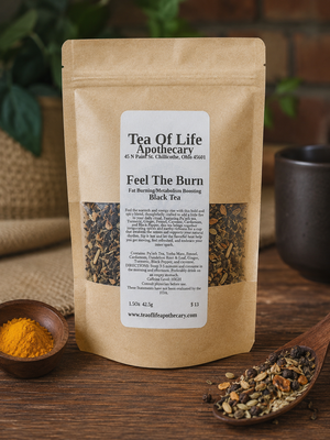 Feel The Burn fat burning and metabolism boosting black tea by Tea of Life Apothecary in a rustic product display with pu'erh tea, turmeric, ginger, fennel, cayenne, cardamom, and black pepper on a wooden table.