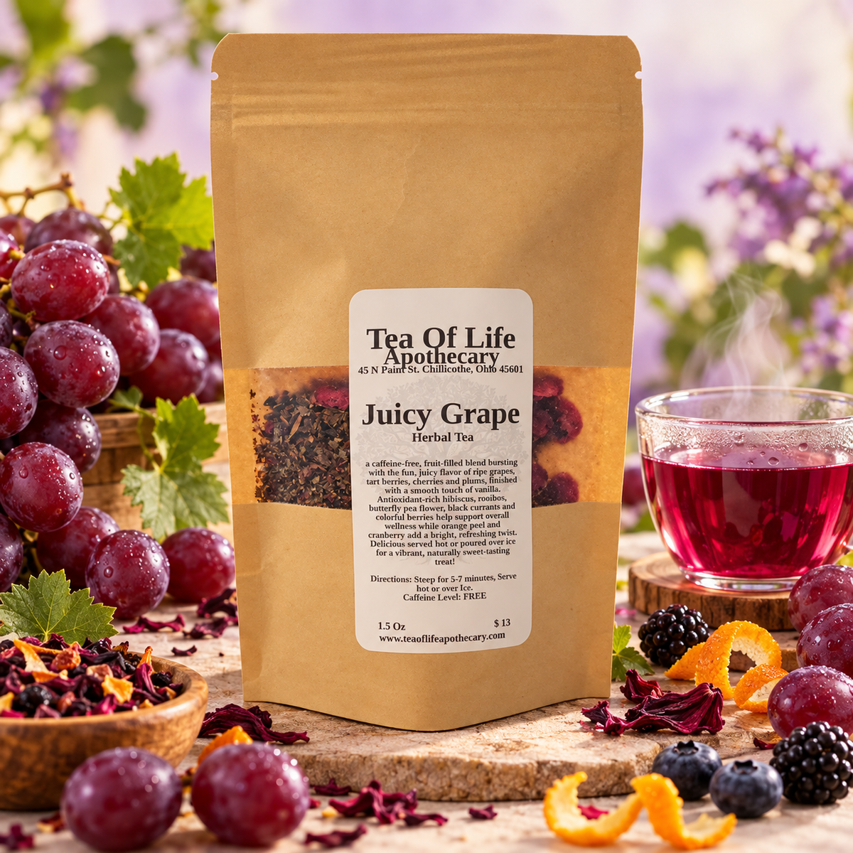 Tea of Life Apothecary Juicy Grape Herbal Tea displayed with fresh grapes, berries, and a cup of ruby-red tea. A fun, caffeine-free fruit and herbal tea blend with a juicy grape-inspired flavor.