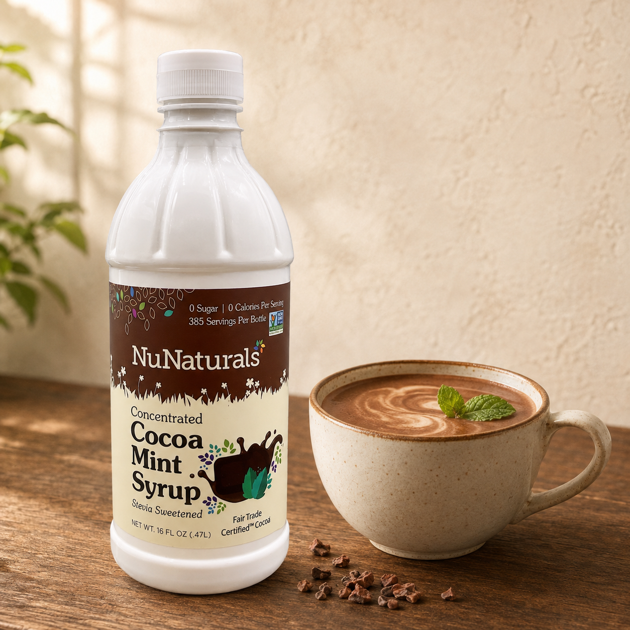 NuNaturals sugar-free Cocoa Mint Stevia Syrup beside a warm cup of mint hot chocolate with fresh mint leaves and cocoa nibs.