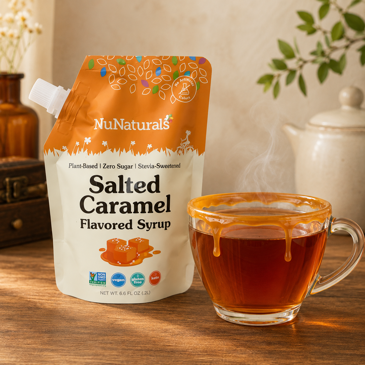 NuNaturals sugar-free salted caramel syrup beside a steaming cup of dessert tea with a glossy caramel-coated rim.