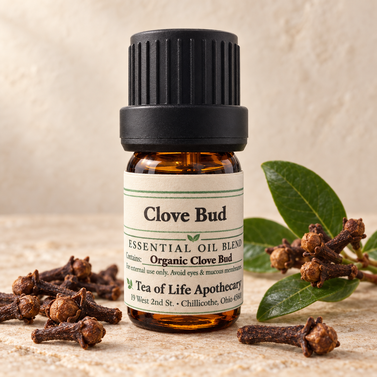 Tea of Life Apothecary Organic Clove Bud Essential Oil in a 5 mL amber glass bottle, displayed with dried clove buds and green clove leaves.